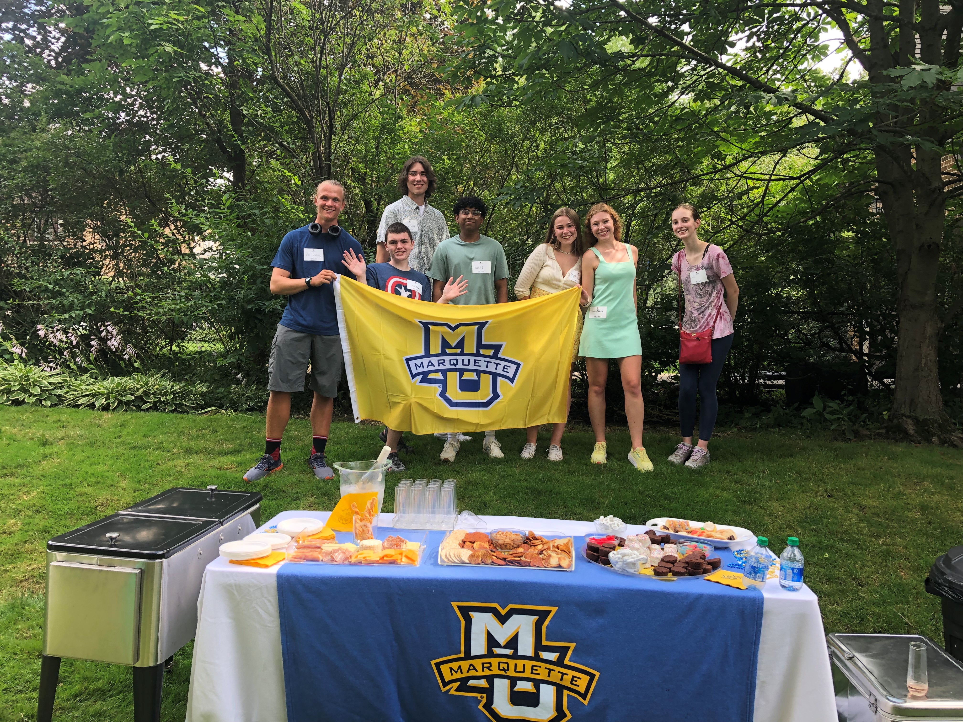 Students holding Marquette flag in backyard